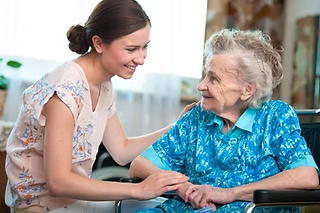 Une jeune soignante prend la main d'une résidente âgée, dans un échange paisible et attentif.